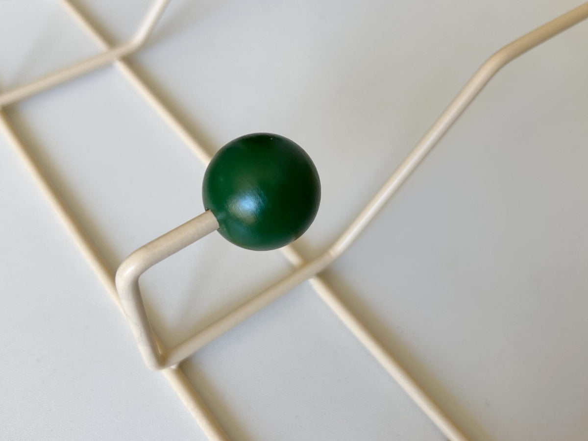 Close-up of a dark green ball hook and cream-colored frame.