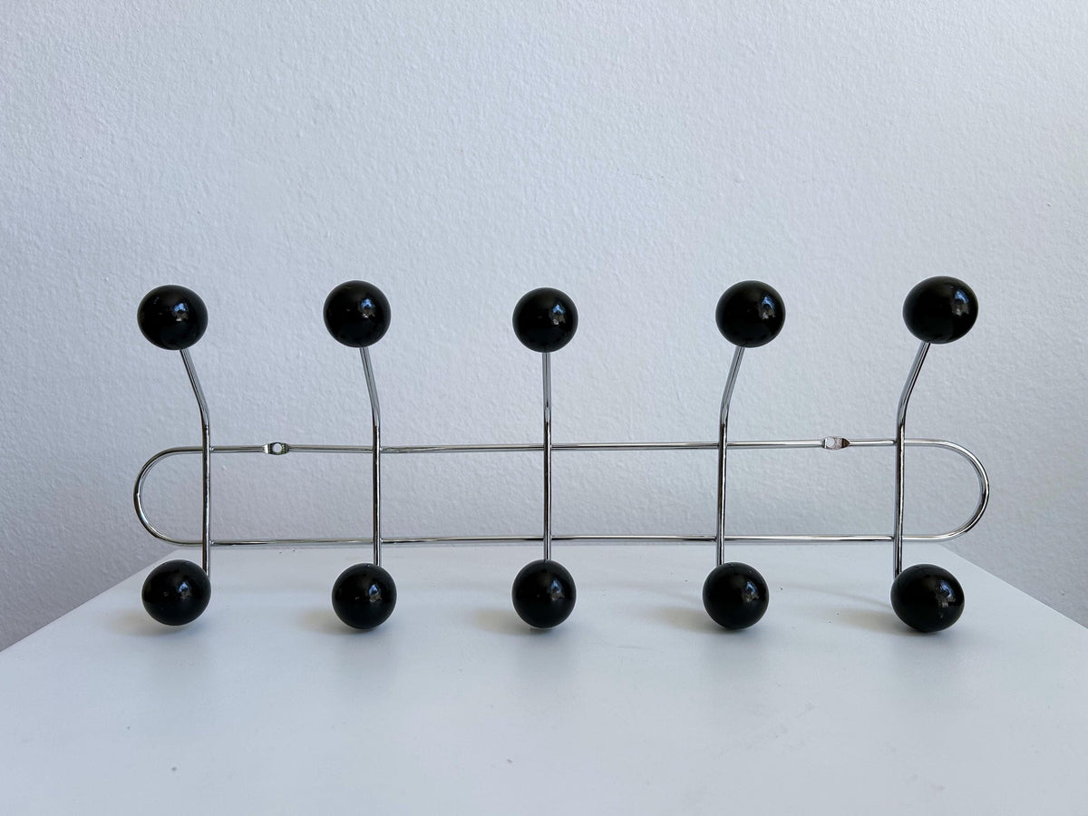Front view of a silver-colored coat rack with ten black ball hooks.