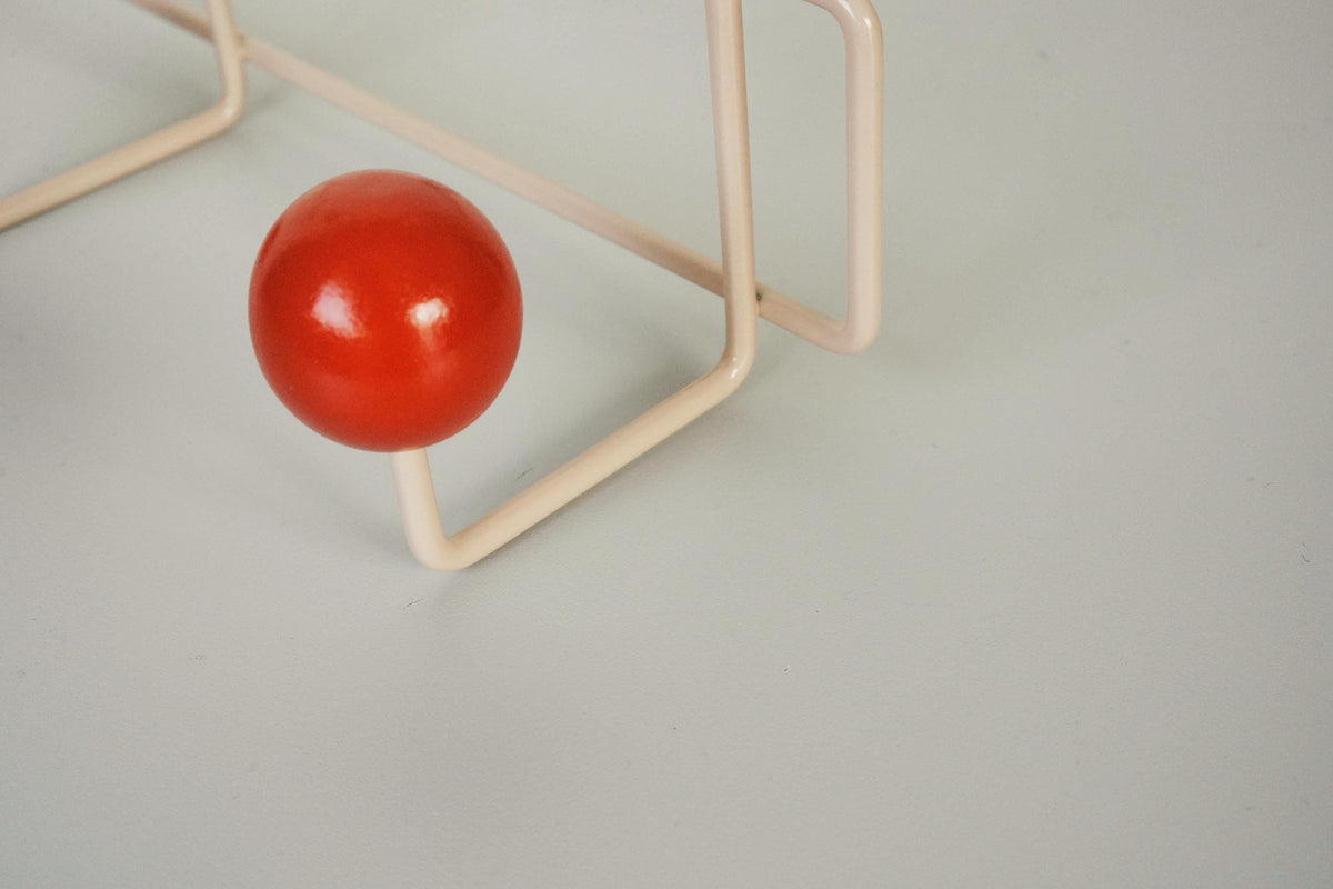 Close-up of a red ball hook on a cream-colored frame.