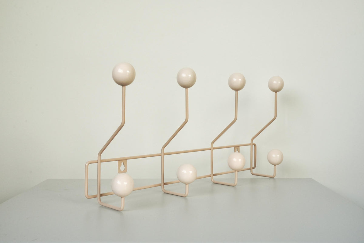 Angled view of a cream-colored coat rack with eight cream ball hooks.