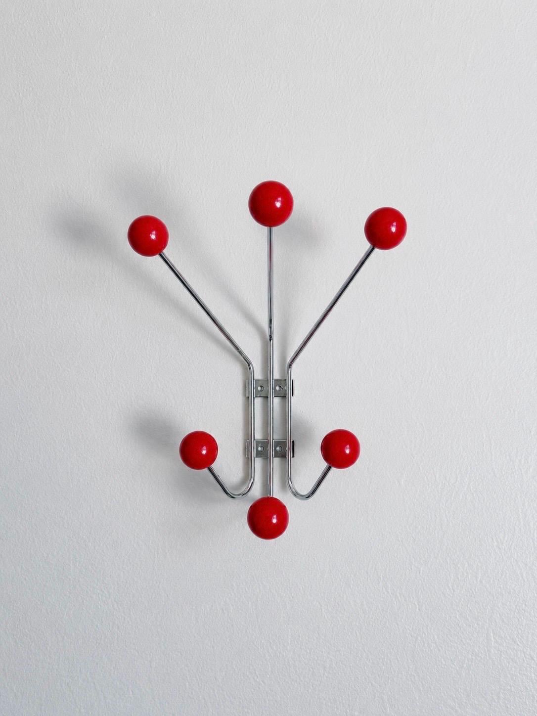 Front view of a wall-mounted hook rack with six red balls.