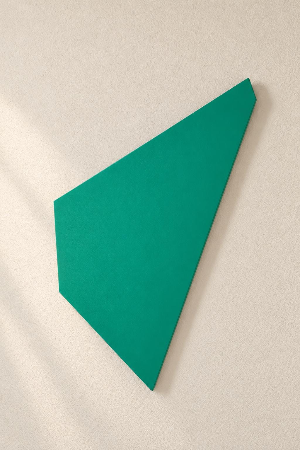 Green angular wall panel mounted on a cream wall.