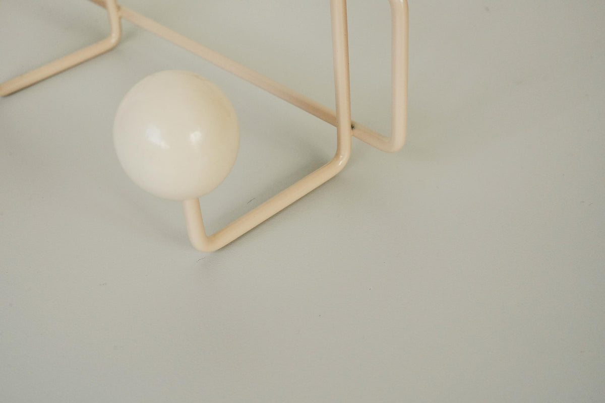 Close-up of a cream ball hook on a cream-colored frame.
