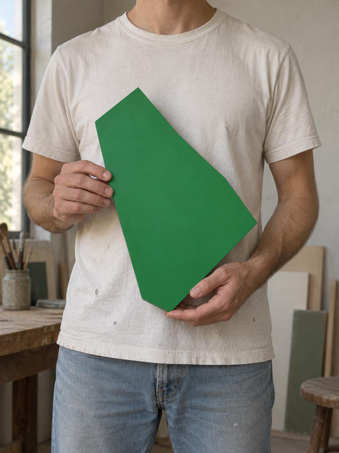 Person holding a green irregular panel in front of a white shirt.
